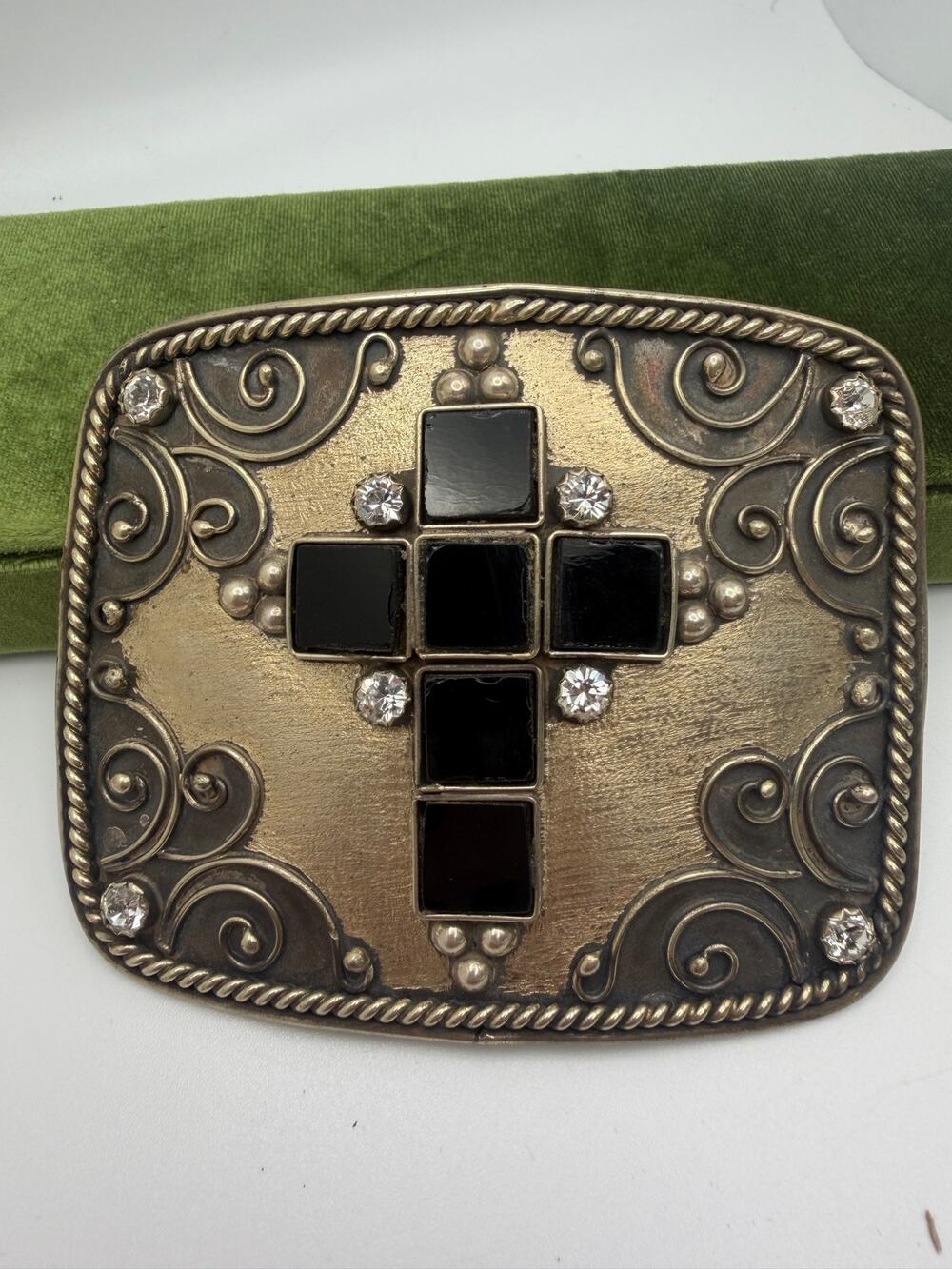 antiqued brass-tone belt buckle featuring an ornate scrollwork design cross